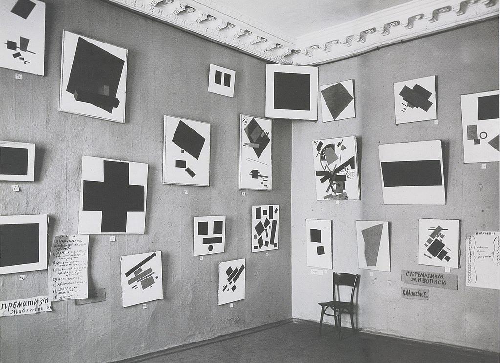 Фотография выставки «0,10», на которой есть 21 картина Малевича. В углу висит «Черный квадрат»